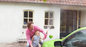 Father and daughter washing a green car